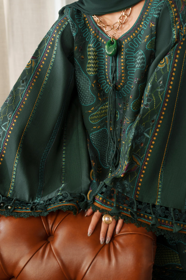 A close-up of a dark green embroidered caftan with intricate patterns and lace trim, worn by a model sitting on a brown leather tufted chair.