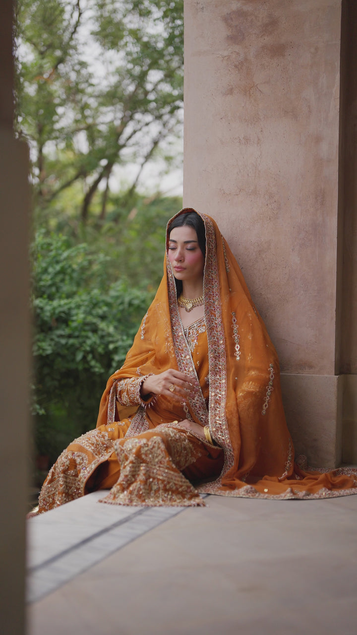 Video preview of NAQSHI Gul-e-Farosh rust formal outfit showing full look with embroidered raw silk gown, chiffon dupatta drape, and tailored trousers.