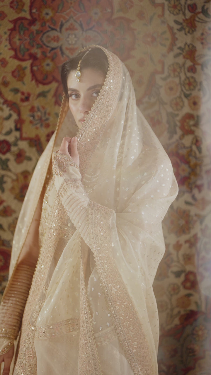 Soft bridal portrait of Tizmat peach 4-piece Nikkah outfit with sheer organza dupatta covering head, modest and calm wedding look, complete ready made formal attire.